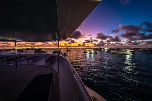 Experience a tranquil sunset cruise aboard a luxury yacht in the Maldives with colorful sky and serene waters.